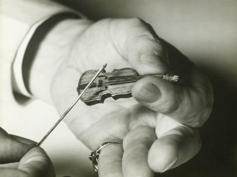 man-holding-tiny-violin-close-up-of-hand