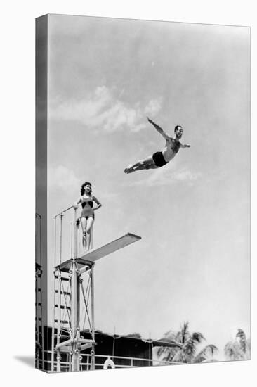 1930s 1940s SHAPELY WOMAN WATCHING MAN SWAN DIVE OFF HIGH DIVING BOARD-H. Armstrong Roberts-Premier Image Canvas