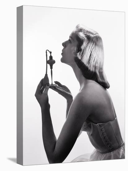 1950s PROFILE PORTRAIT STYLISH ELEGANT YOUNG WOMAN HOLDING UP PERFUME ATOMIZER SPRAY BOTTLE-Panoramic Images-Premier Image Canvas