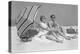 1960s COUPLE IN SUNGLASSES SITTING ON BEACH BLANKET WITH LEGS EXTENDED WITH UMBRELLA-H. Armstrong Roberts-Premier Image Canvas