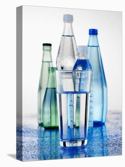 A Glass in Front of Mineral Water Bottles-Alexander Feig-Premier Image Canvas