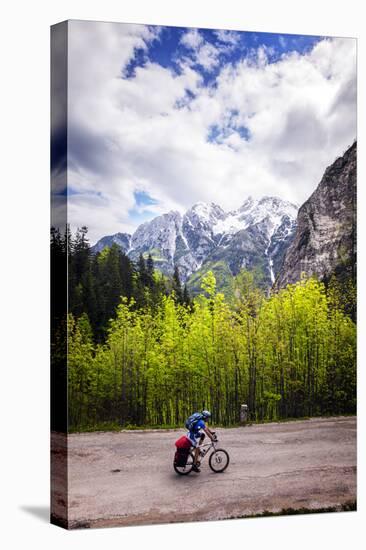 A Lone Cyclist Travels Along a Mountain Road with Trees and the Julian Alps in the Background-Sean Cooper-Premier Image Canvas