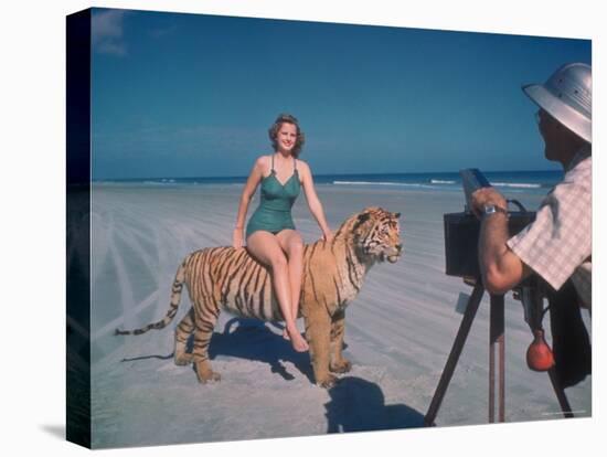 Bathing Beauty Sitting on Back of Large Tiger on Beach as Photographer Sets Up Camera-Eliot Elisofon-Premier Image Canvas