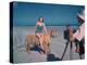 Bathing Beauty Sitting on Back of Large Tiger on Beach as Photographer Sets Up Camera-Eliot Elisofon-Premier Image Canvas