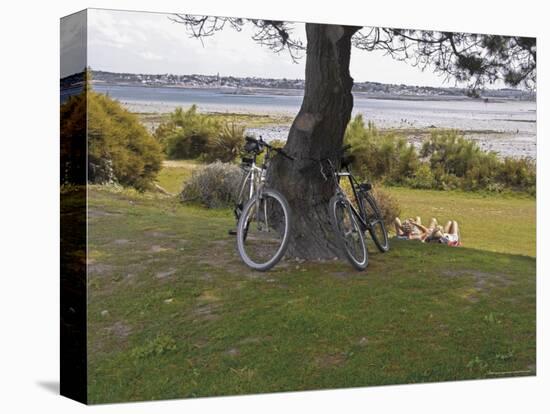 Bicycles by Tree and Couple Relaxing on the Grass, St. Pol De Leon, Carentac in Distance, Brittany-David Hughes-Premier Image Canvas