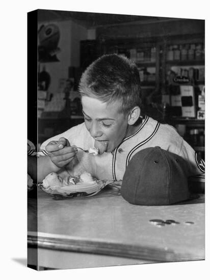 Boy Wearing Baseball Uniform Eating Banana Split at Soda Fountain Counter-Joe Scherschel-Premier Image Canvas