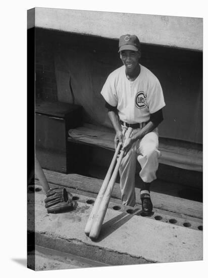 Chicago Cub's Ernie Banks, Stooping in the Dug-Out Holding Two Bats Against Cincinnati Reds-John Dominis-Premier Image Canvas