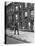 Children Watching a Policeman Walk His Beat in Front of Apartment Buildings-Ed Clark-Premier Image Canvas