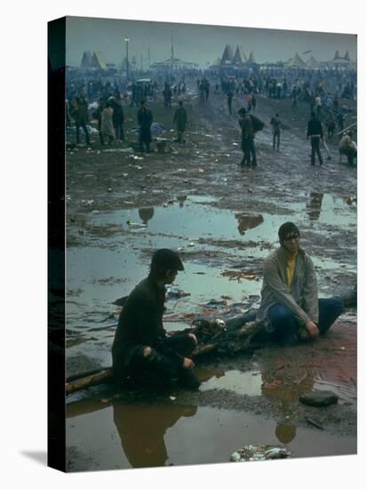 Chuck Morgan Sitting in the Mud and Water with a Friend, During Woodstock Music and Art Fair-John Dominis-Premier Image Canvas