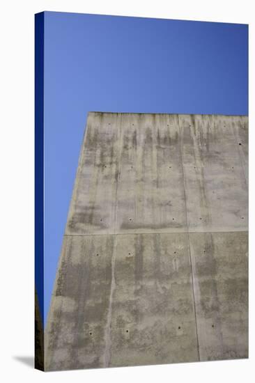 Concrete grey wall with structure and inclusions as a background in front of sky blue cloudless-Axel Killian-Stretched Canvas