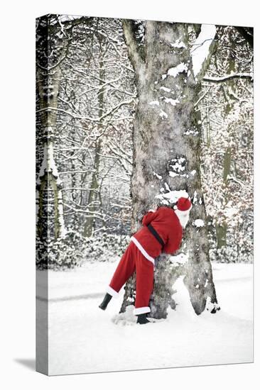 Father Christmas in Snow Behind Tree-null-Premier Image Canvas