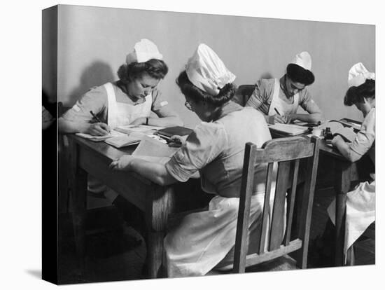 Four Young British Student Nurses Making Notes Together from Medical Textbooks-null-Premier Image Canvas