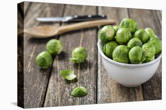 Fresh Brussels Sprouts in White Bowl on Wooden Table-Jana Ihle-Premier Image Canvas