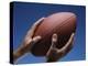 Hands Holding Football with Blue Background-null-Premier Image Canvas