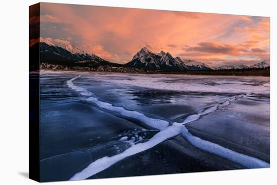 Ice cracks along Abraham Lake in Banff, Canada at sunset with pink clouds and scenic mountains-David Chang-Premier Image Canvas