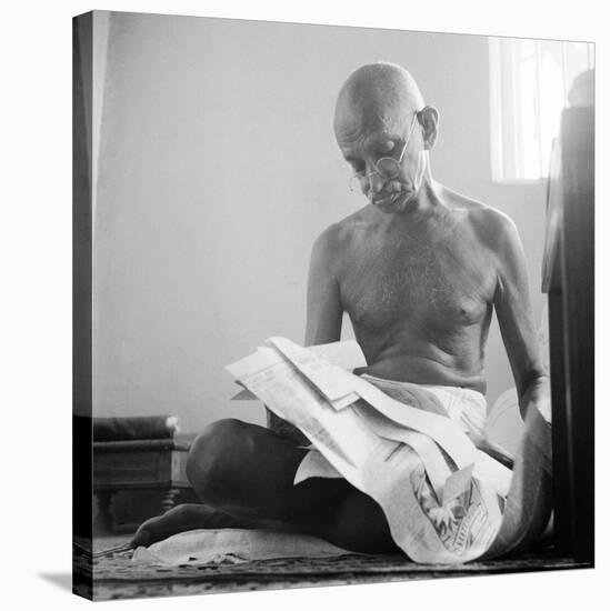 Indian Leader Mohandas Gandhi Reading as He Sits Cross Legged on Floor, at Home-Margaret Bourke-White-Premier Image Canvas