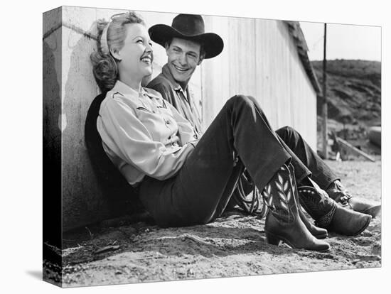 Laughing Couple in Western Attire Sitting on the Ground-null-Stretched Canvas