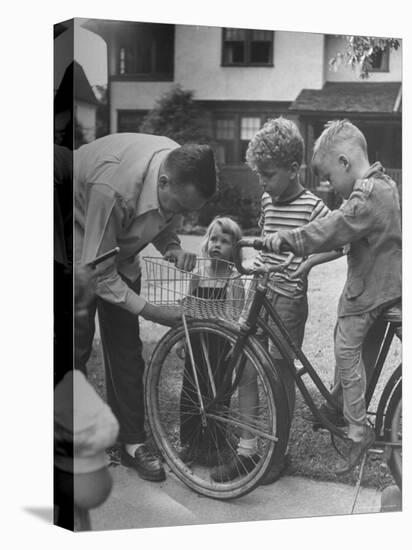 Man Fixing Basket on Bicycle as Children Watch Attentively-Nina Leen-Premier Image Canvas