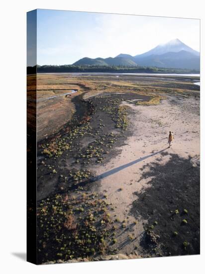 Man Walking on Dry Lake Bed with Llaima Volcano in Distance, Conguillio National Park, Chile-Aaron McCoy-Premier Image Canvas