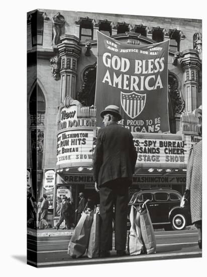 Man with Shopping Bags in Front of Million Dollar Theatre Emblazoned with God Bless America Banner-Bob Landry-Premier Image Canvas