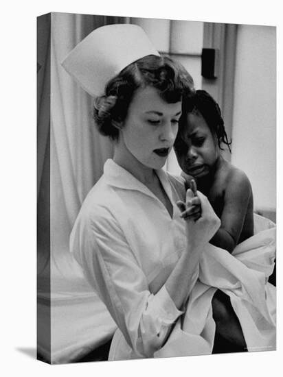Nurse Holding African American Girl in Her Arms, Examining Her Finger-John Dominis-Premier Image Canvas