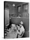 Nurse Sitting at Table with Medical Supplies While Doctors Examine Patient in Background-Wallace Kirkland-Premier Image Canvas