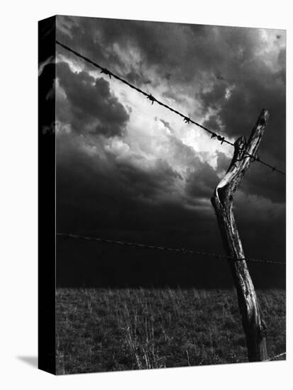 On a Small Farm, Ominous Clouds Overhead, Outlined by Barbed Wire Fencing-Nat Farbman-Premier Image Canvas
