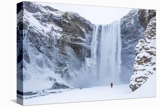 One Person in Red Jacket Walking in the Snow Towards Skogafoss Waterfall in Winter-Neale Clark-Premier Image Canvas