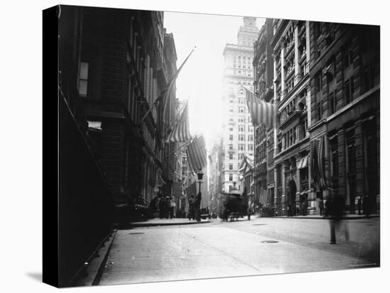People and Horse Drawn Carts on Wall St, Where American Flags Fly from Buildings-George B^ Brainerd-Premier Image Canvas