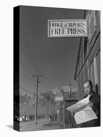 Roy Takeno, editor of Manzanar Free Press, reading the paper at the Manzanar War Relocation Center-Ansel Adams-Premier Image Canvas