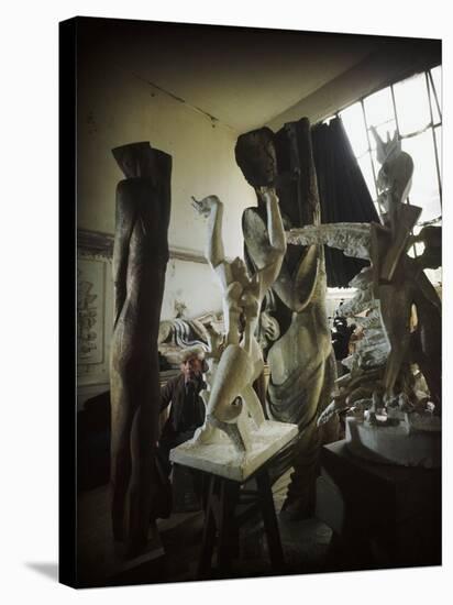 Russian Sculptor Ossip Zadkine Sitting in His Paris Studio Among Towering Sculptures-Gjon Mili-Premier Image Canvas