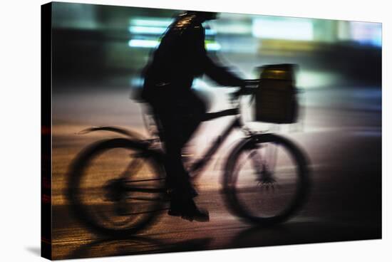 Side View With Motion Blur Of A Delivery Man Riding A Bicycle At Night In Downtown Manhattan-Ron Koeberer-Stretched Canvas