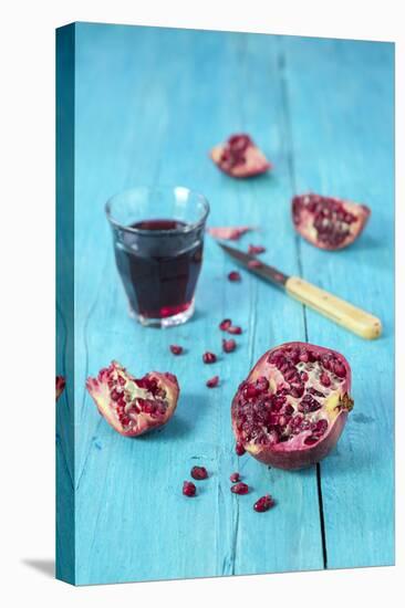 Sliced Pomegranate and a Glass of Pomegranate Juice on Turquoise Wooden Table-Jana Ihle-Premier Image Canvas