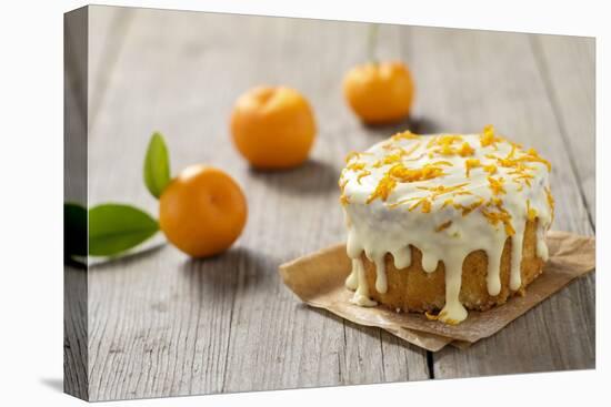 Small Orange Cake with White Icing on Wooden Table-Jana Ihle-Premier Image Canvas