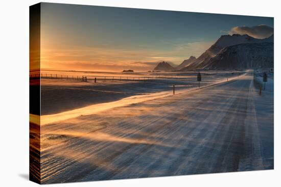 Snow Blows across an Icelandic Road at Sunrise with Mountains Looming in the Distance-Alex Saberi-Premier Image Canvas