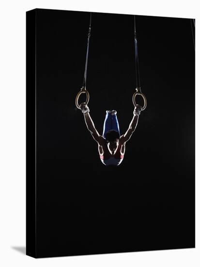 Teenage (16-17) Male Gymnast Practicing on Rings against Black Background-Thomas Barwick-Premier Image Canvas