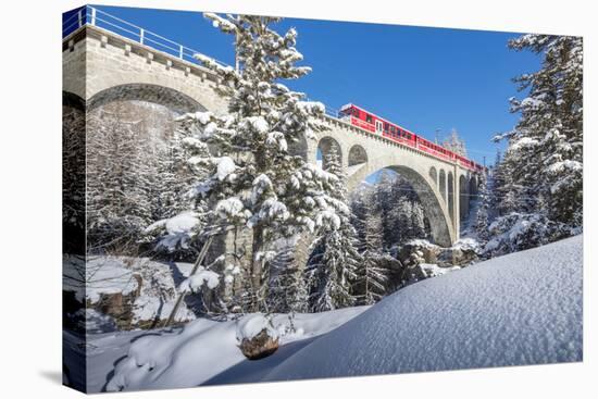 The red train on viaduct surrounded by snowy woods, Cinuos-Chel, Canton of Graubunden, Engadine, Sw-Roberto Moiola-Premier Image Canvas