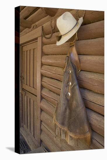 USA, Montana, Livingston, cowboy hat and chaps hanging on barn wall.-Merrill Images-Premier Image Canvas