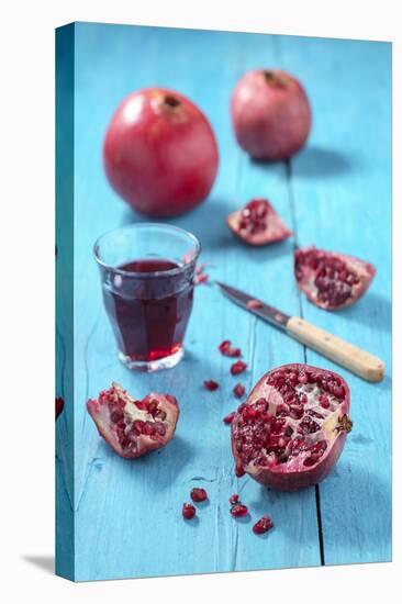 Whole and Sliced Pomegranate and Glass of Pomegranate Juice on Turquoise Wooden Table-Jana Ihle-Premier Image Canvas