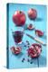 Whole and Sliced Pomegranate and Glass of Pomegranate Juice on Turquoise Wooden Table-Jana Ihle-Premier Image Canvas