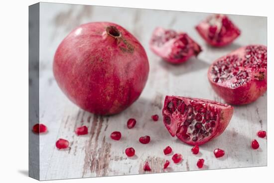 Whole Pomegranate and Pomegranate Pieces on White Wooden Table-Jana Ihle-Premier Image Canvas