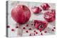 Whole Pomegranate and Pomegranate Pieces on White Wooden Table-Jana Ihle-Premier Image Canvas