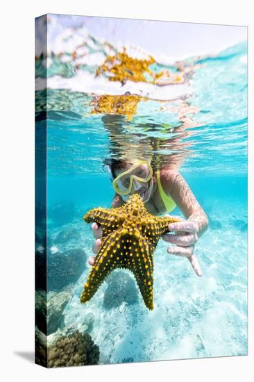 Woman showing a yellow starfish underwater in the tropical lagoon, Zanzibar, Tanzania-Roberto Moiola-Premier Image Canvas