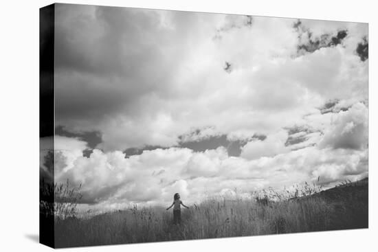 Young Girl Standing in a Field with Clouds-Clive Nolan-Premier Image Canvas