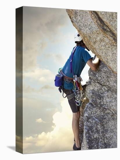 Young man rock climbing up a vertical cliff-null-Premier Image Canvas