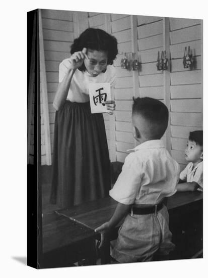 Young School Teacher Explaining to a Little Chinese Boy the Writings on Card That She Is Holding-null-Premier Image Canvas