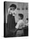 Young School Teacher Explaining to a Little Chinese Boy the Writings on Card That She Is Holding-null-Premier Image Canvas