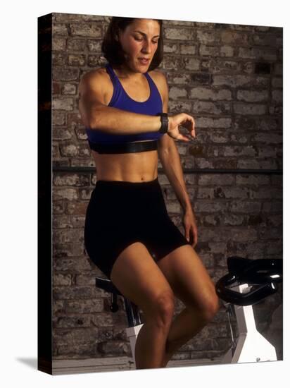 Young Woman Exercising on a Stationary Bike Checking her Heart Rate-null-Premier Image Canvas