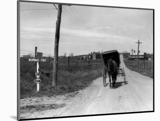 1920s-1930s Amish Man Driving Buggy Down Rural Dirt Road in Farm Country-null-Mounted Photographic Print