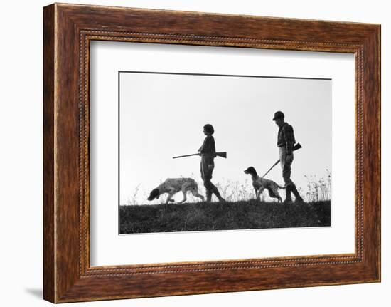 1920s 1930s ANONYMOUS SILHOUETTE MAN AND WOMAN HUNTERS CARRYING GUNS EACH WITH A HUNTING DOG-H. Armstrong Roberts-Framed Photographic Print